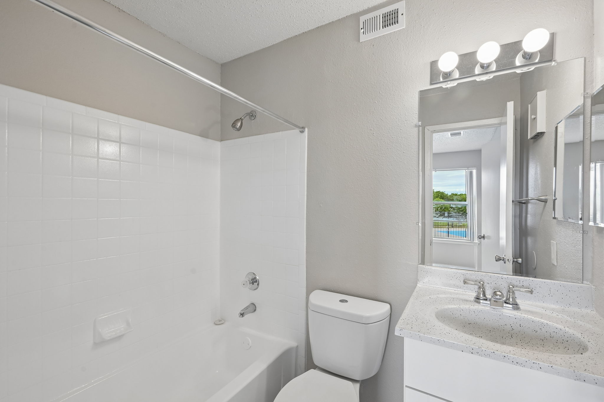 A white bathroom with a toilet, sink, and mirror.
